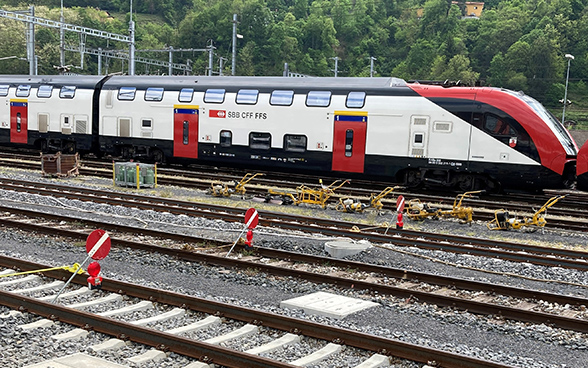 Cartelli rossi con una striscia bianca indicano la chiusura di tre binari. Sullo sfondo un treno a lunga percorrenza delle FFS.